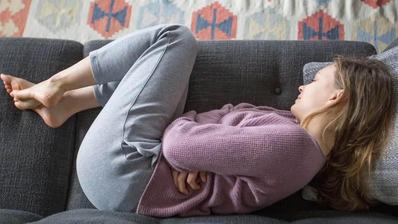 Una mujer con dolor abdominal aparece tumbada en el sofá